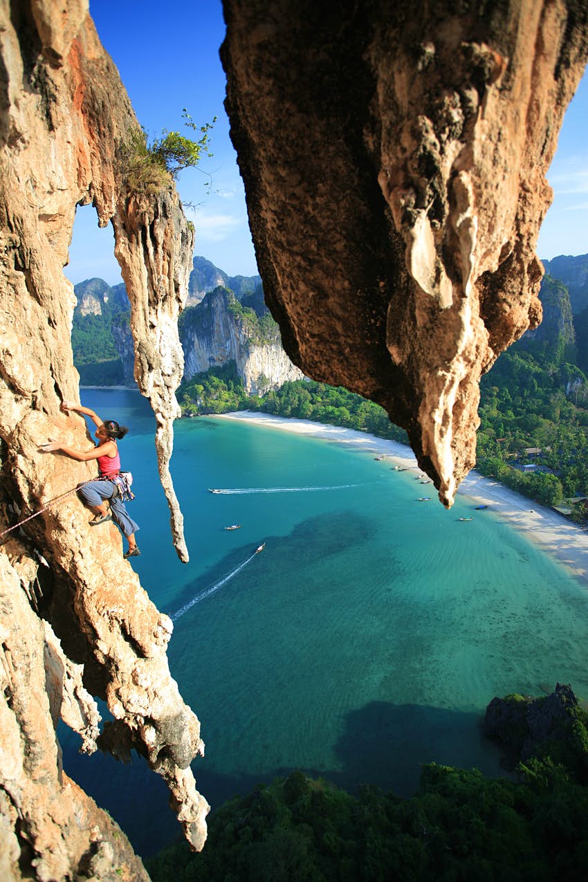 Female rock climber climbing a rock face in Railay southern Thailand. 